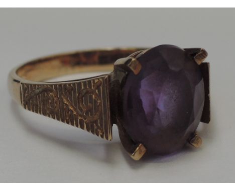 A ladies dress ring having an oval amethyst stone in a raised basket mount with stylised shoulders on a 9ct gold loop