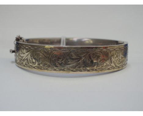 A white metal hinged bangle stamped SILVER/9ct front having scroll engraved decoration