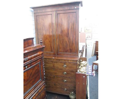 An early 19th century mahogany full height cabinet having cupboard doors over two short and three long cock beaded drawers on