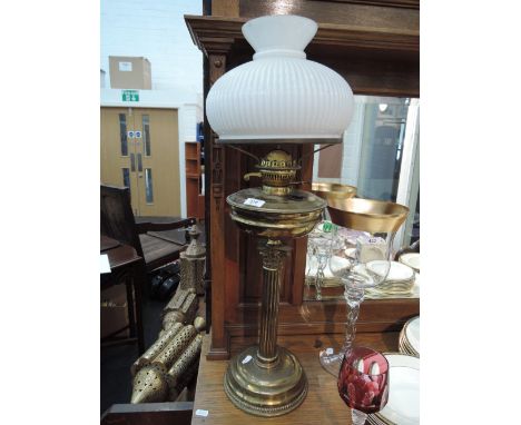A Victorian brassed oil lamp having ribbed glass shade, central reservoir on Corinthian column and a brassed oil lamp base