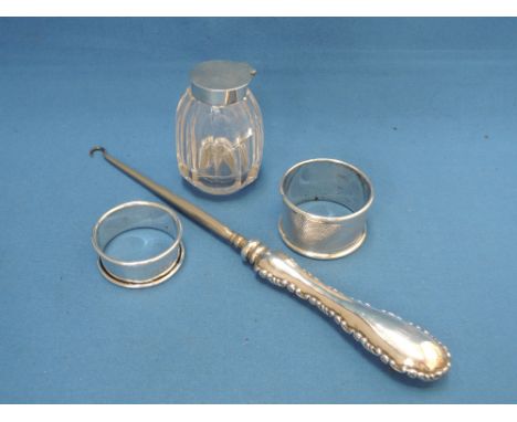An HM silver handled button hook, two HM silver napkin rings and a glass ink pot with HM silver lid