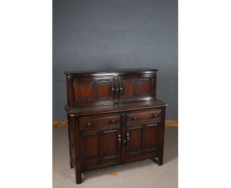 Ercol dark wood sideboard, the top with two panelled doors, opening to reveal storage space, the base with two drawers above 