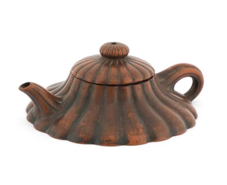 A Chinese Yixing teapot, in the squat form of a chrysanthemum splaying to a flat base, the handle and spout imitating the ste