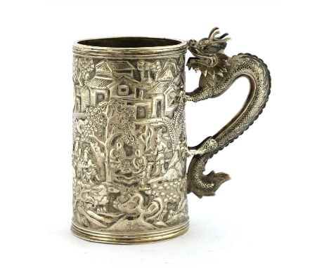A Chinese silver mug, 19th century, of tapering cylindrical form, moulded with figures in a garden, the handle in the shape o