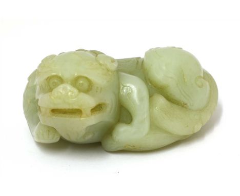 A Chinese jade carving, of a recumbent Buddhist lion, its hair engraved in details, the stone of greyish-white tone, 9.5cm lo