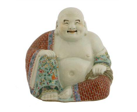 A Chinese famille rose Budai, Republic period (1912-1949), wearing a garment painted with brickwork and florets against a tur