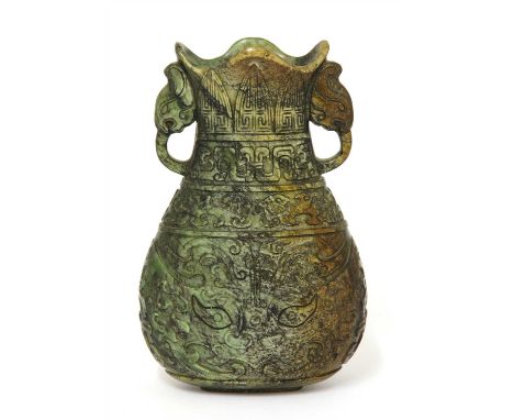 A Chinese jade vase, late Ming dynasty, the compressed pear-shaped body with a lobed rim, carved with a taotie mask below sty