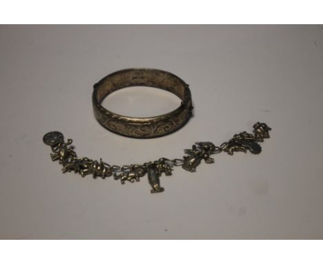 A HALLMARKED SILVER BANGLE AND A WHITE METAL CHARM BRACELET (2)