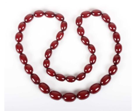 A single row necklace of graduated oval cherry coloured imitation amber beads, first half of the 20th century, possibly Bakel