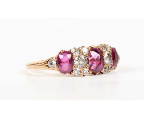 A gold, ruby and diamond ring, mounted with three oval cut rubies, otherwise mounted with old cut cushion shaped diamonds, un