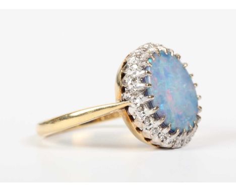 An 18ct gold, opal doublet and diamond cluster ring, claw set with the oval opal doublet within a surround of single cut diam
