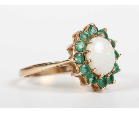 A 9ct gold, opal and emerald oval cluster ring, claw set with the oval opal within a surround of circular cut emeralds, Birmi