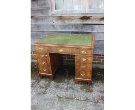 An early 20th century walnut double pedestal desk with green leather tooled lined top over nine drawers, on bracket feet, 43"