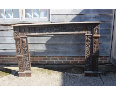 A 19th century carved oak fireplace surround with frieze panel carved figures, horses and windmill, and sides carved masks an