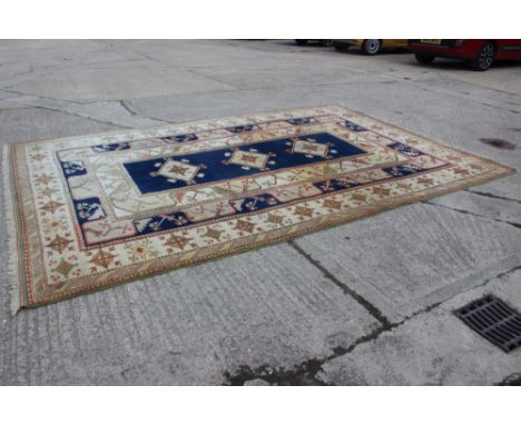 A Caucasian wool pile carpet with central guls and geometric and floral designs, on a terracotta ground, in shades of natural