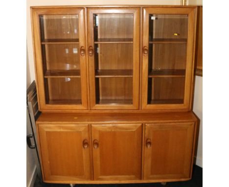 Ercol light oak unit fitted three glazed doors over triple cupboard door base.