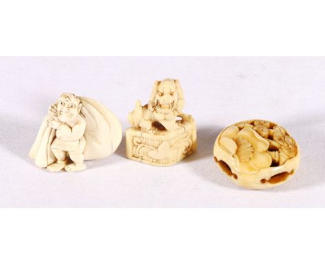 Manju netsuke, pierced and carved with bamboo and flowers, an ivory oni carrying a large sack and a carved lion dog. (3)