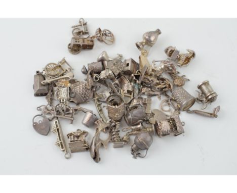 A collection of silver charms to include a tankard, a fish, and many others, 165.4g.