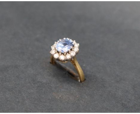 A sapphire and diamond cluster ring set with a central oval faceted sapphire, approximately 7mm x 6mm surrounded by round bri