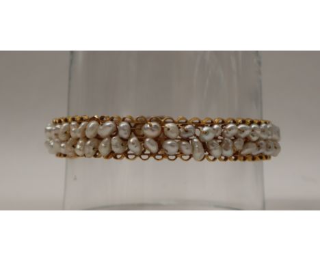 A yellow metal pearl set bangle, with two rows of irregular pearls, approximately 28 grams