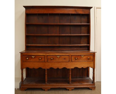 An 18th century oak dresser, the moulded cornice above three shelves, the base with a planked rectangular top and three drawe