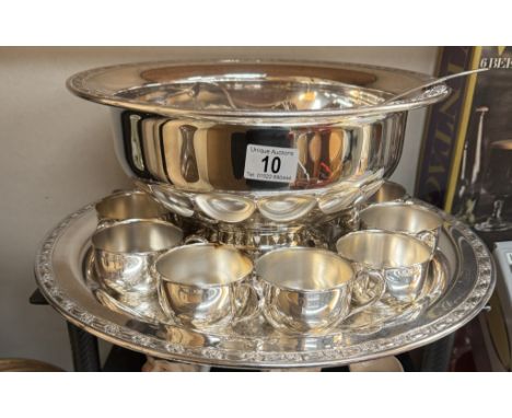 A large silver plated punch bowl on tray with ladle and drinking vessels