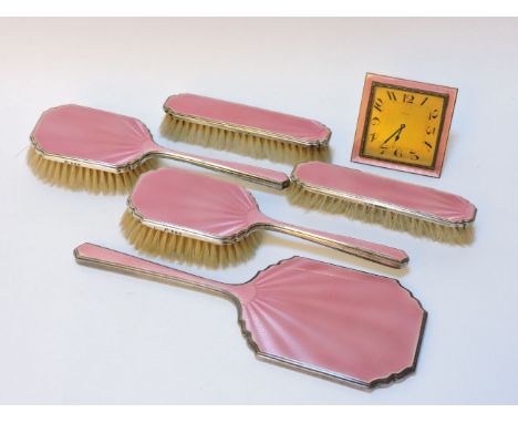 A silver and pink enamel vanity set, to include mirror, hair brush, clothes brush, and a matching clock