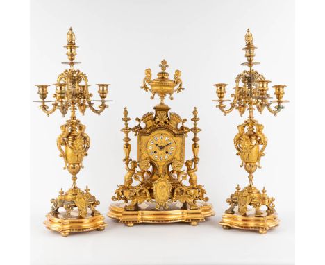 A three-piece mantle garniture clock and candelabra, gilt spelter, decorated with putti.Circa 1900.Height of the candelabra: 