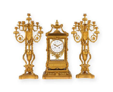 An imposing three-piece mantle garniture clock and candelabra.Gilt bronze in Louis XVI style, richly decorated with garlands,