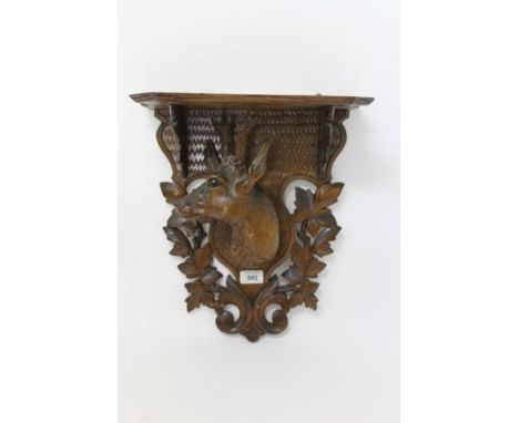 Late 19th / early 20th century Black Forest carved wood wall bracket, the shaped shelf above projecting deer's head with shie