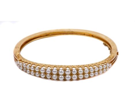 Victorian pearl bangle with two graduated rows of half pearls, on a yellow metal hinged bangle with pierced setting, in fitte