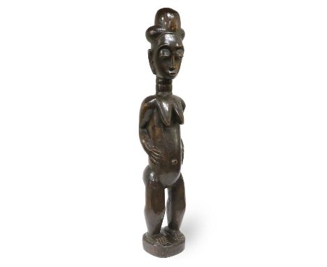 A Baule, Ivory Coast Large Fertility Figure, of dark patinated wood, the female figure standing with trilobed coiffure, oval 