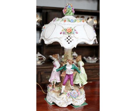 A Continental Porcelain Table Lamp, late 20th century, the shade set with lithophane panels and adorned with applied flowers,