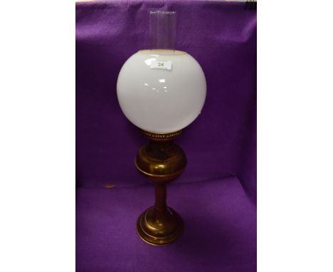 A brass table top oil lamp with spherical milk shade.