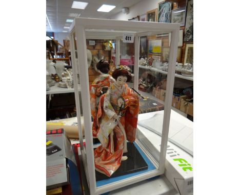 A cased Japanese doll figure playing a drum