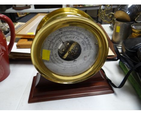 Modern brass barometer mounted on a wooden plinth