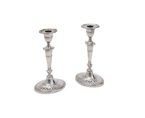 A pair of George V silver candlesticks on navette-shaped bases with fluted decoration, reeded borders, and detachable nozzles