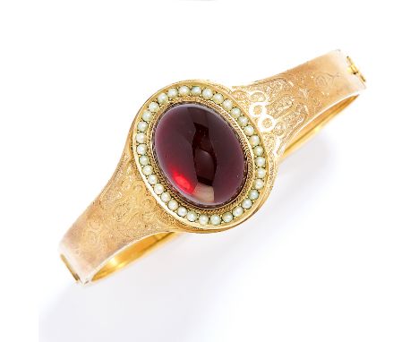 ANTIQUE GARNET AND PEARL BANGLE in high carat yellow gold, comprising a cabochon garnet in a border of seed pearls with engra