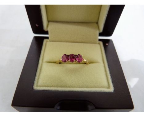 A three stone pink ring. In gold marked 18k. Size R. 2.9g gross