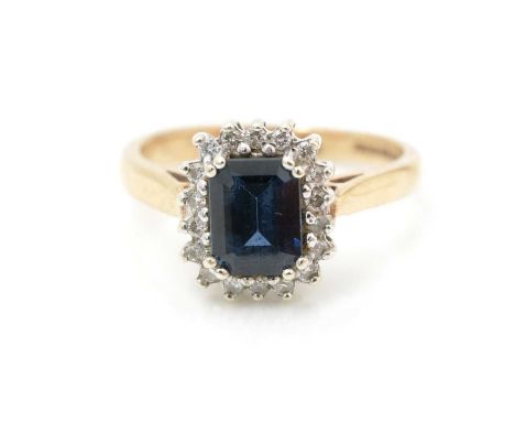 A sapphire and diamond cluster ring, the rectangular step-cut sapphire surrounded by brilliant-cut diamonds, in 9ct white gol