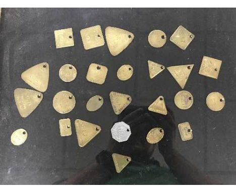 Twenty six miner's lamp checks (tokens or tallies) in a glass display case 