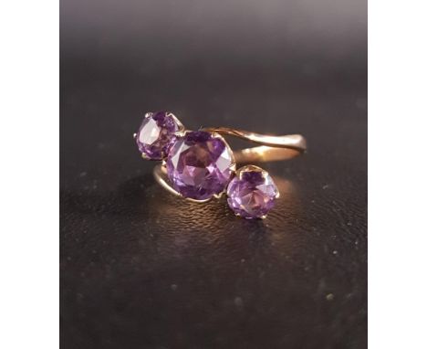 ATTRACTIVE AMETHYST THREE STONE RINGin twist setting, the central round cut amethyst approximately 2cts flanked by smaller am