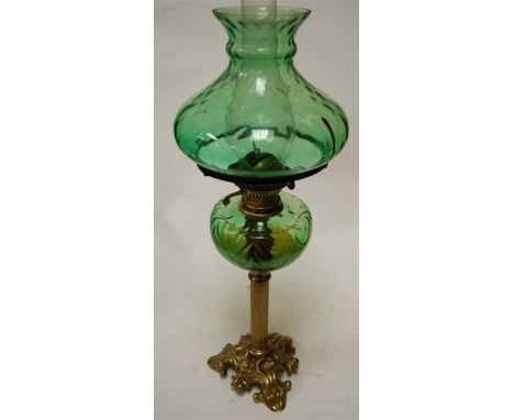 A Victorian oil lamp, having a green glass shade above a cut glass reservoir, on a brass column and scrolled base