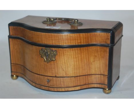 An early 19th century satinwood and ebony banded tea caddy, or serpentine form, having a hinged lid opening to reveal fitted 