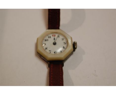 An early 20th century nickel and mother of pearl wristwatch having enamel dial with Arabic numerals and leather strap in asso