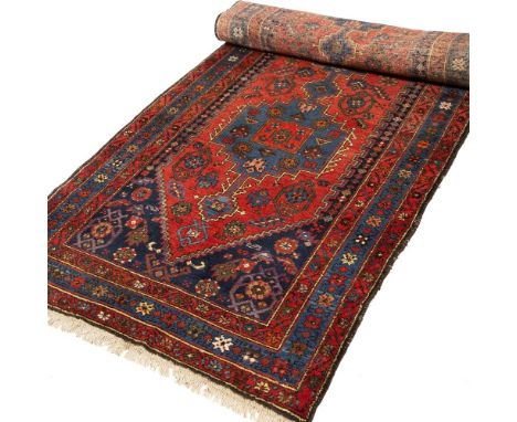 A Hamadan brick red ground runner rug, the inter-connecting central blue ground medallions within a triple starred border, 48