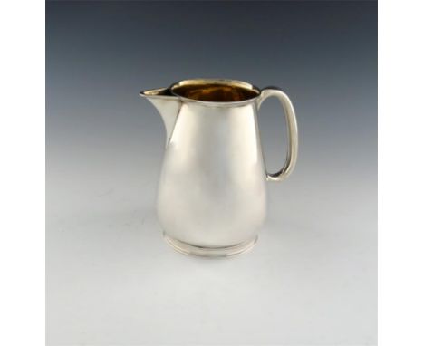 A Victorian silver water jug, by Rupert Favell, London 1886, tapering circular form, scroll handle, gilded interior, on a cir