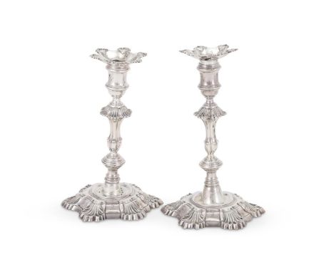 A PAIR OF GEORGE II CAST SILVER CANDLESTICKS WILLIAM GOULD, LONDON 1750 With shaped circular and shell sconces, reel capitals