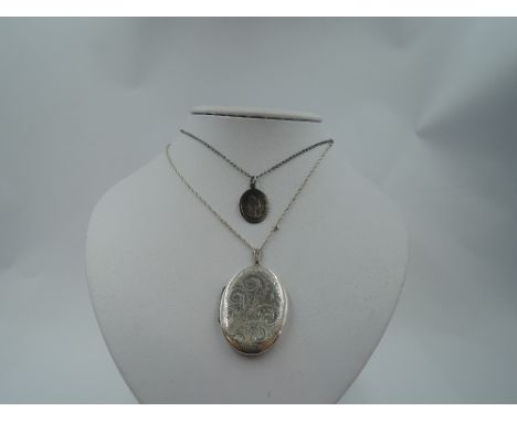 An oval white metal locket stamped silver bk &amp; fnt having engraved scroll decoration on a white metal chain stamped sterl