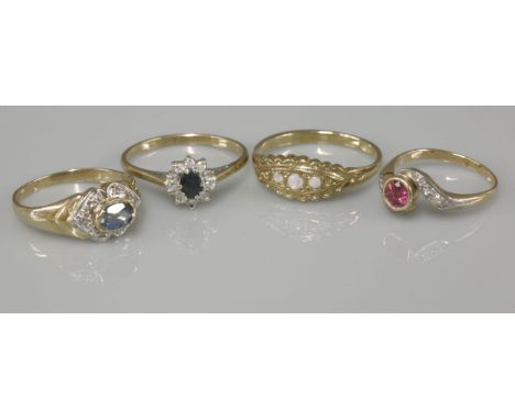 A 9ct gold blue and topaz diamond ring, a 9ct gold sapphire and diamond oval cluster ring, a ruby and diamond crossover ring 